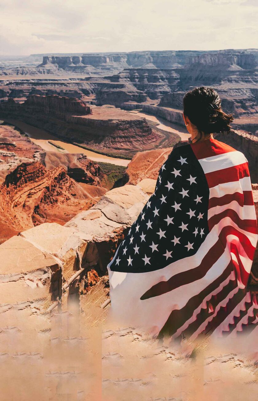 Une femme portant le drapeau américain regarde le Grand Canyon