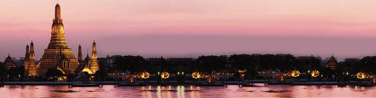 Vue panoramique du Wat Arun, Temple de l'Aube, à Bangkok, avec les lumières du crépuscule se reflétant sur le fleuve Chao Phraya et un ciel rosé.