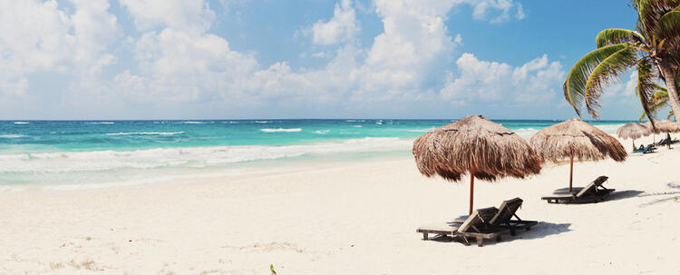 Chaises longues avec parasols de paille sur la plage, vagues dans la mer