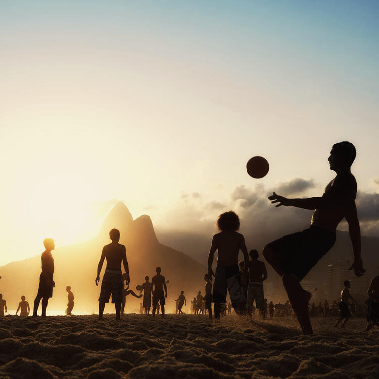 Des gens sur la plage au coucher du soleil avec un ballon