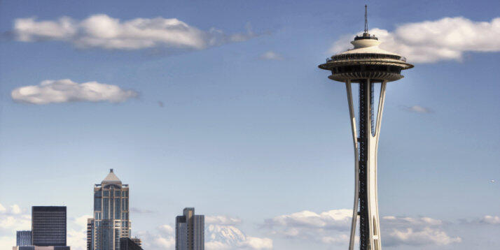 La Space Needle di Seattle sotto un cielo azzurro con nuvole sparse e il Monte Rainier sullo sfondo.