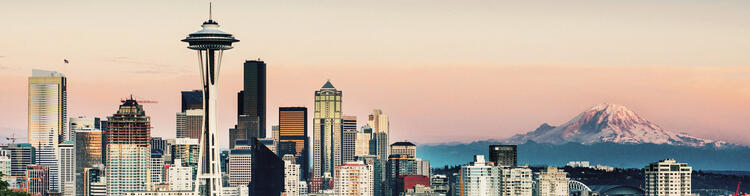 Skyline di Seattle al tramonto con la Space Needle in primo piano e il Monte Rainier sullo sfondo innevato.