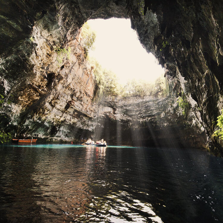 Der berühmten Melissani See auf der Insel Kefalonia in Griechenland. Der See ist durch eine Höhle unterirdisch verbunden und das Wasser ist türkisblau. Es gibt einige Boote zu sehen mit Touristen .