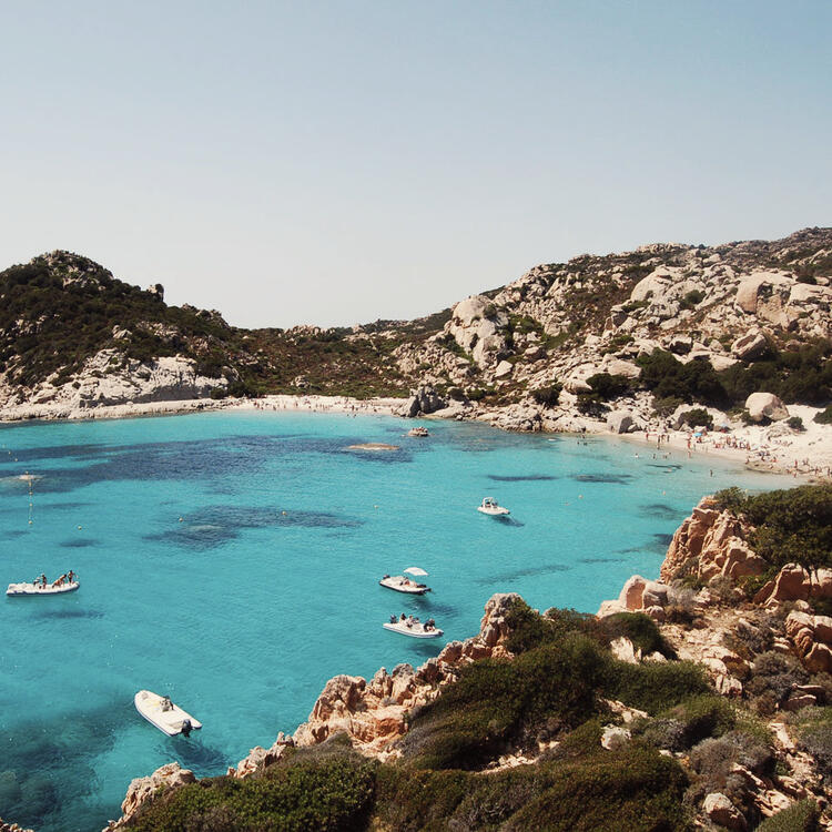 Ansicht von oben, Luftaufnahme von einem Smaragd und transparente Mittelmeer mit einem weißen Strand und einige Boote und Yachten. Costa Smeralda, Sardinien, Italien