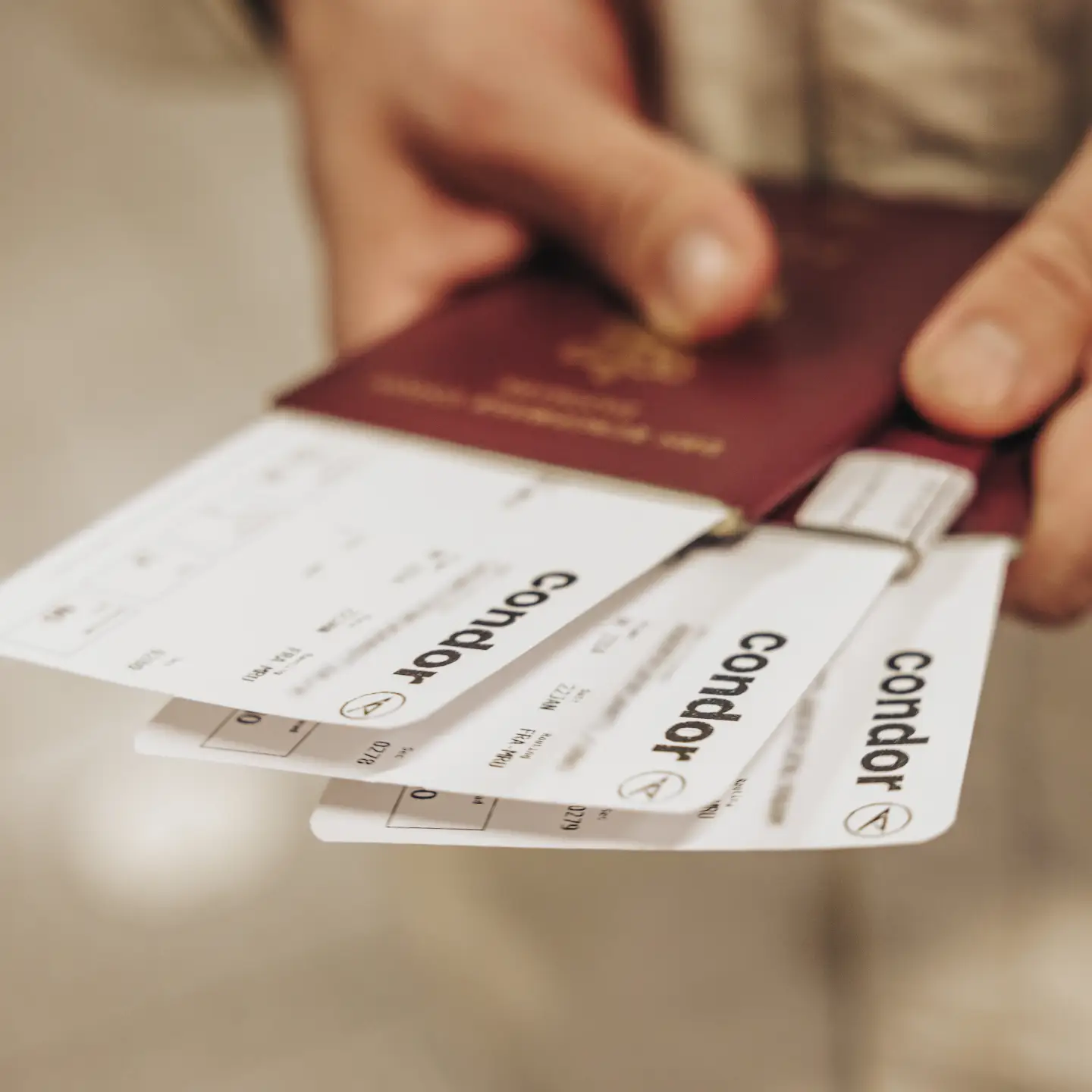 Un passager tient un passeport et plusieurs cartes d’embarquement Condor en main.