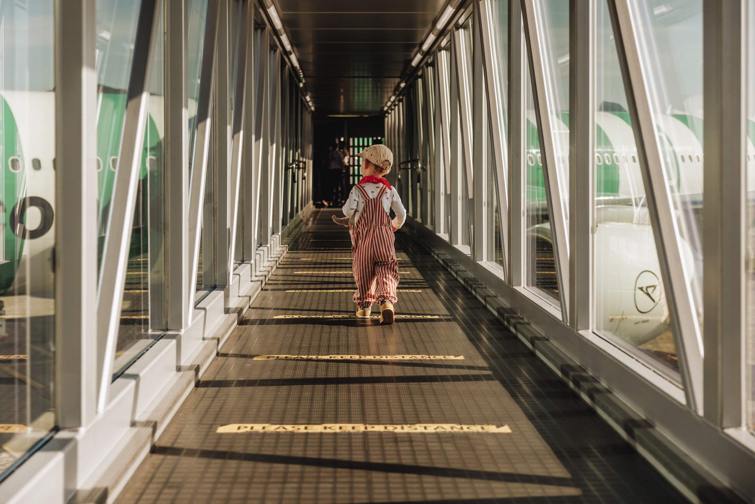 Un niño pequeño corriendo por el puente de pasajeros hacia el avión.