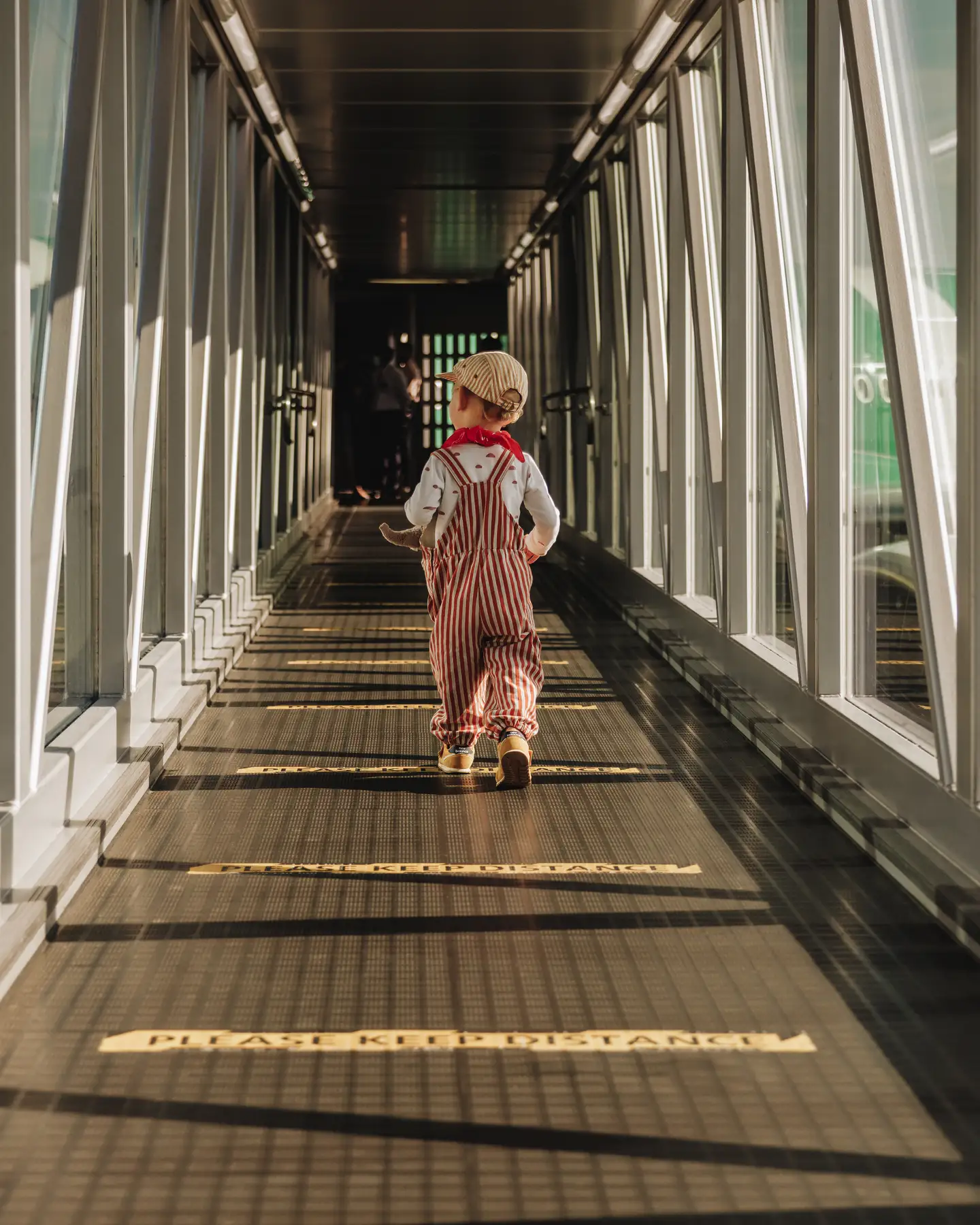 Un niño pequeño corriendo por el puente de pasajeros hacia el avión.