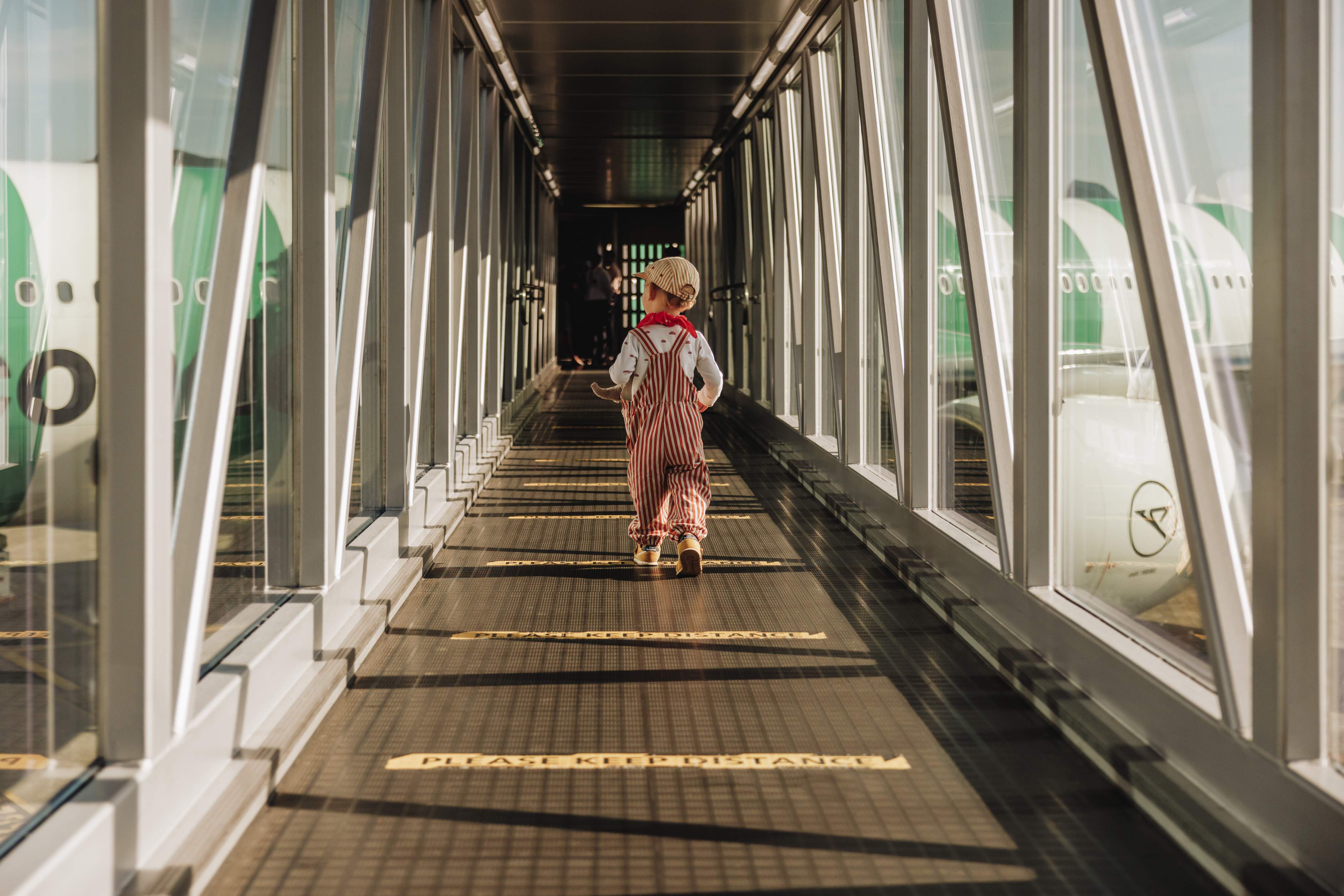 Een jongetje dat over de passagiersbrug het vliegtuig in rent