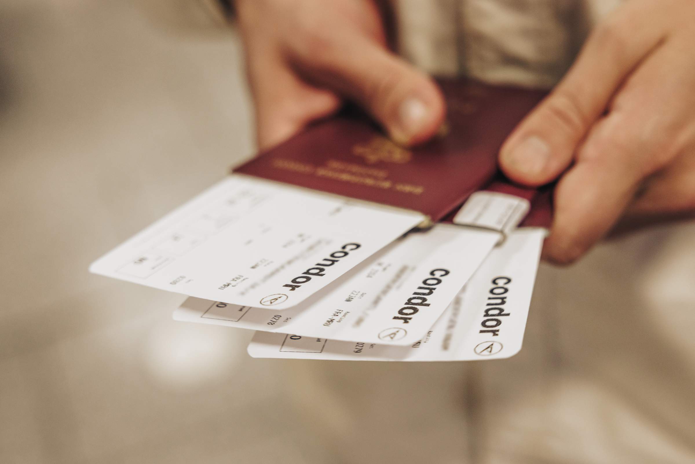 Un viajero con un pasaporte y varias tarjetas de embarque de Condor en la mano.
