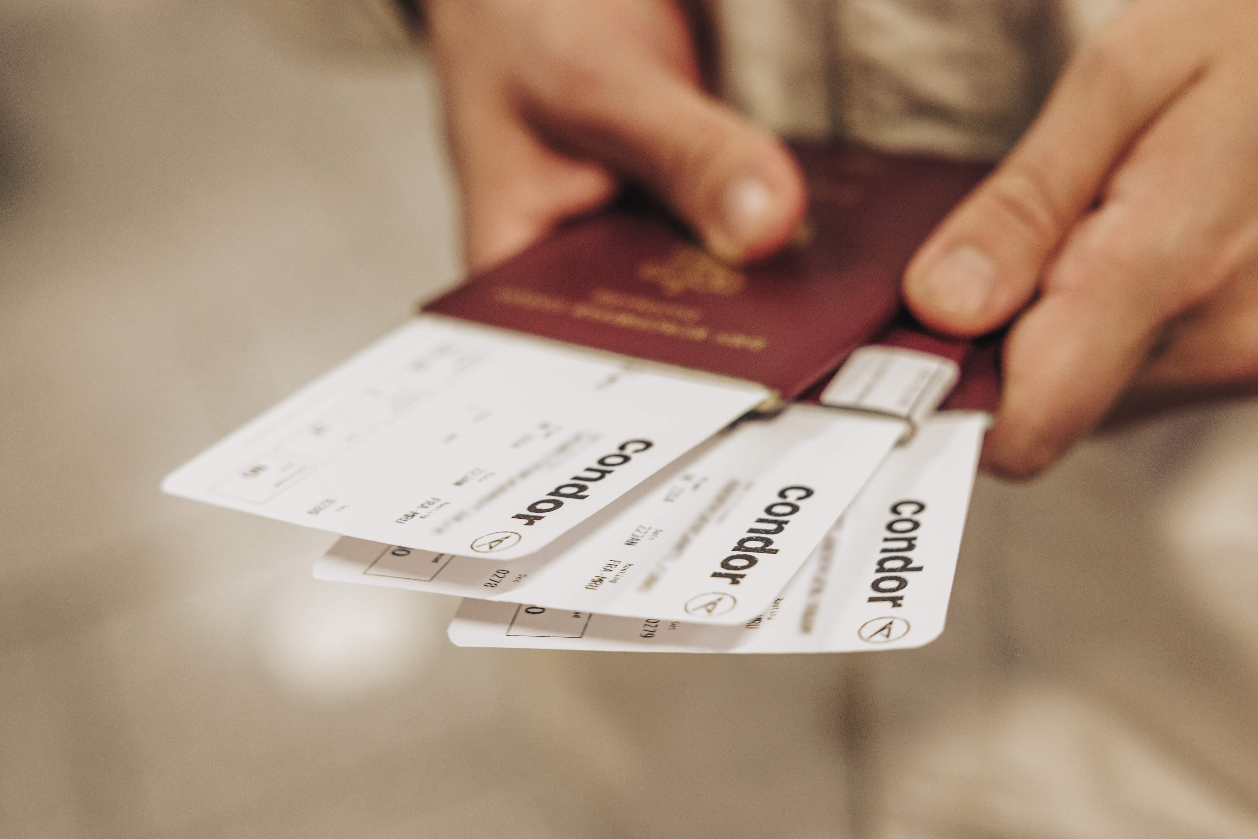 Un viajero con un pasaporte y varias tarjetas de embarque de Condor en la mano.