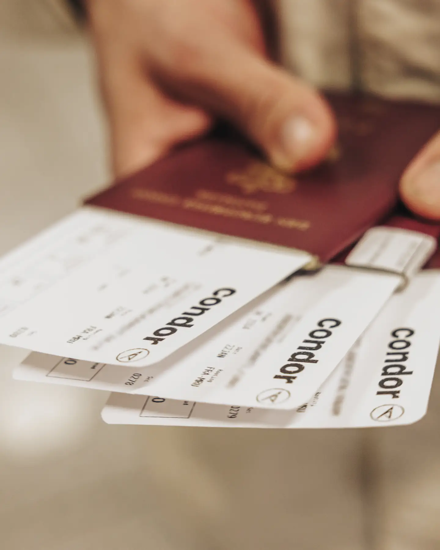 Un viajero con un pasaporte y varias tarjetas de embarque de Condor en la mano.
