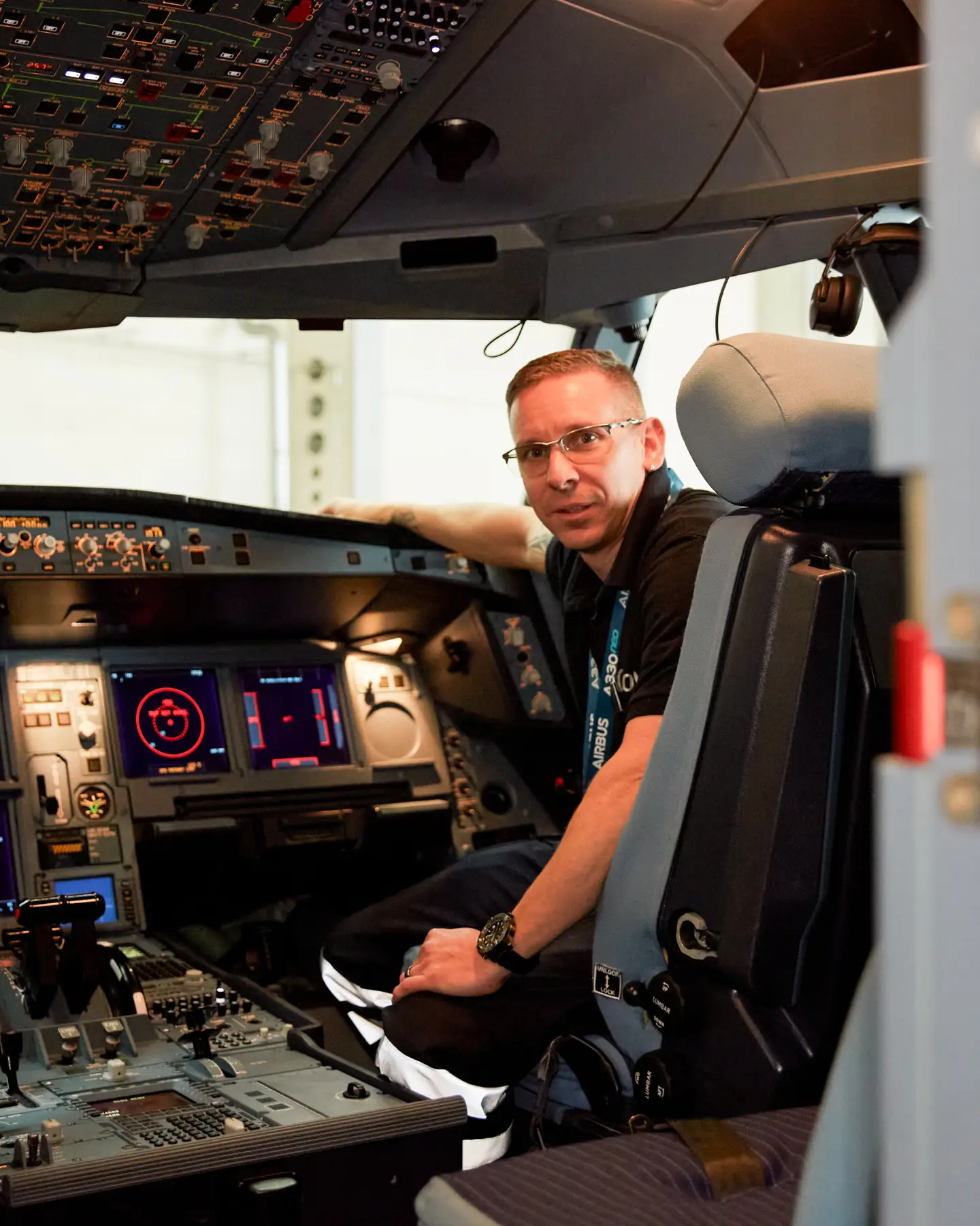 An aircraft systems mechanic sits in the cockpit of an aircraft during a test and looks into the camera.