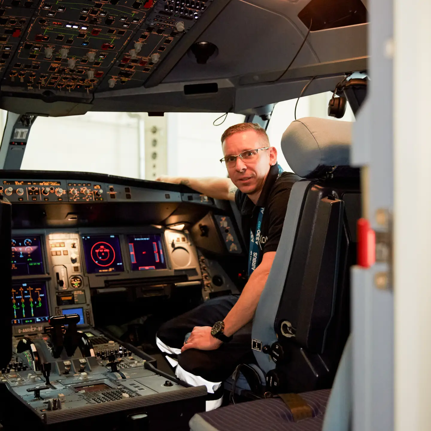 An aircraft systems mechanic sits in the cockpit of an aircraft during a test and looks into the camera.