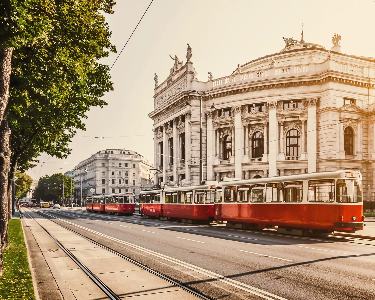 Famous Vienna Ringstrasse with historic Burgtheater (national theatre) and traditional red electric tram at sunrise in Vienna, Austria.