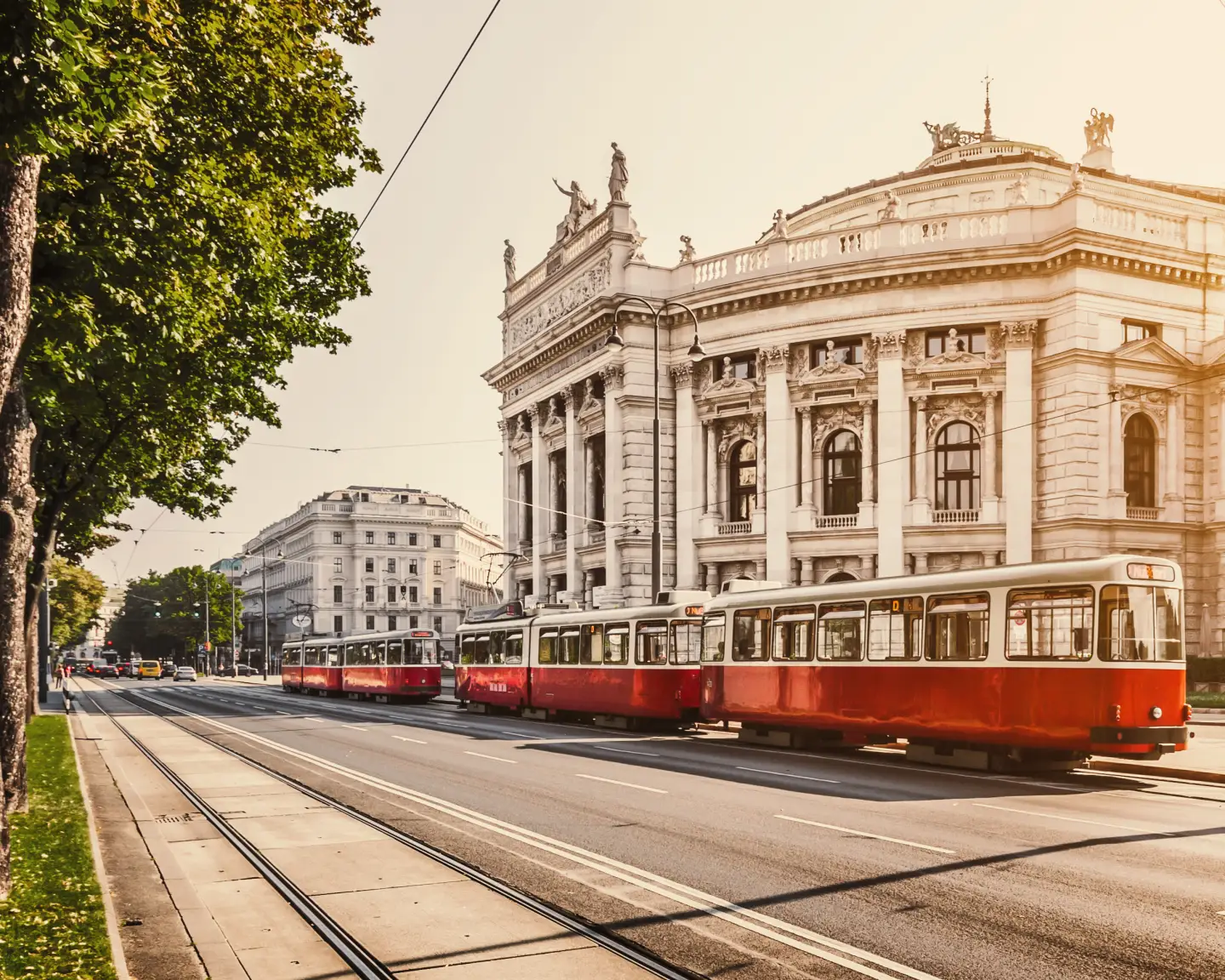 Rote Straßenbahn fährt an dem Wiener Burgtheater entlang – ein Wahrzeichen der österreichischen Hauptstadt Wien.
