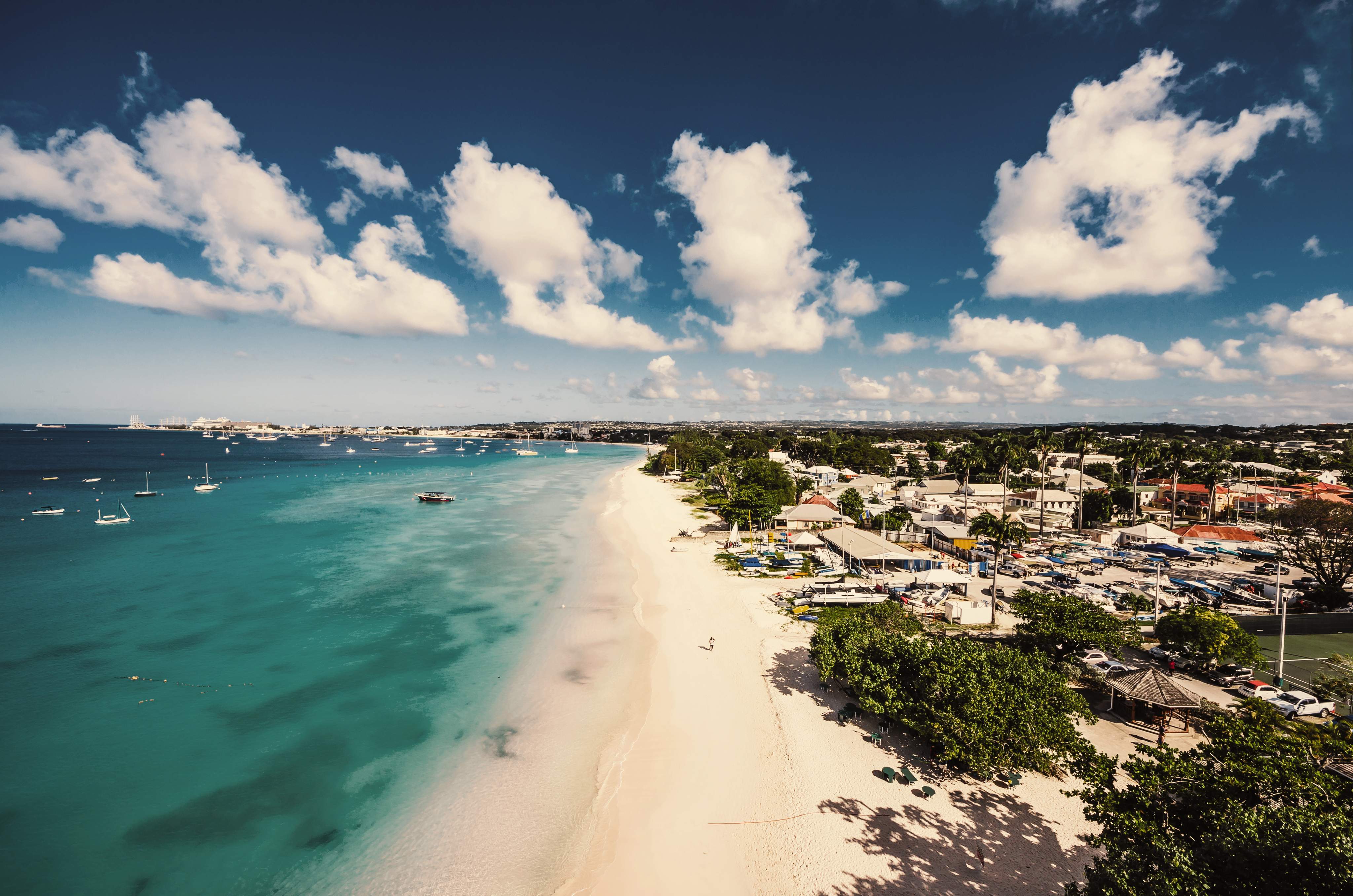 Küstenansicht von Barbados mit verschiedenen Städten entlang des Strandes und einigen Booten auf dem Wasser.