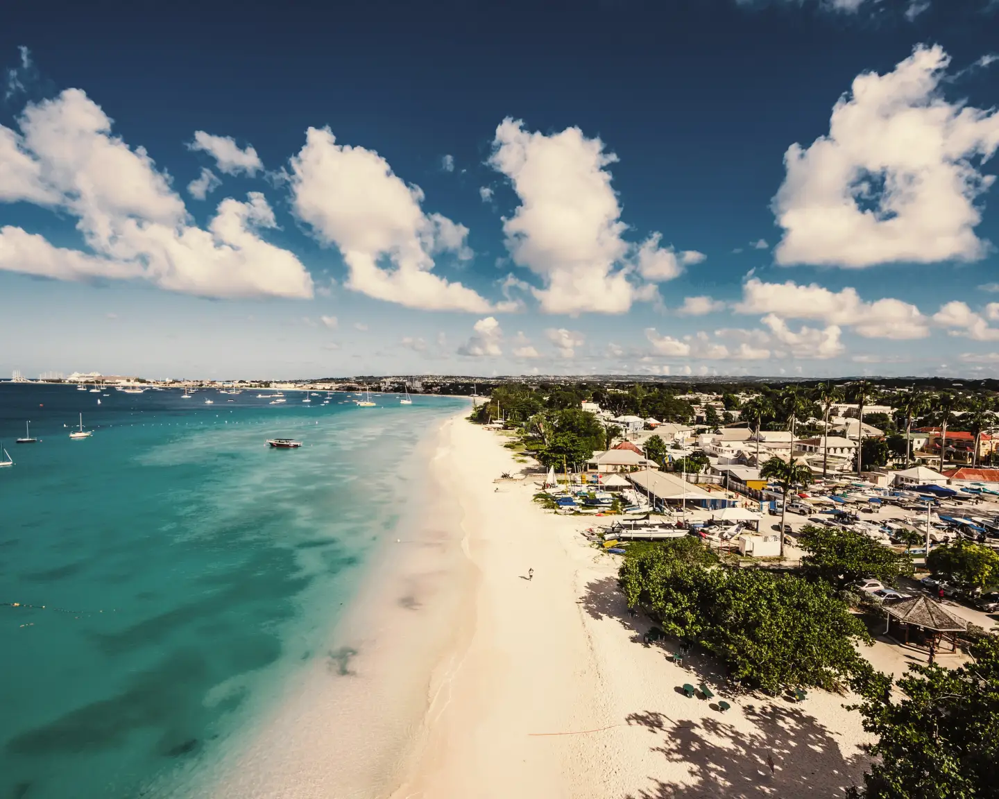 Küstenansicht von Barbados mit verschiedenen Städten entlang des Strandes und einigen Booten auf dem Wasser.
