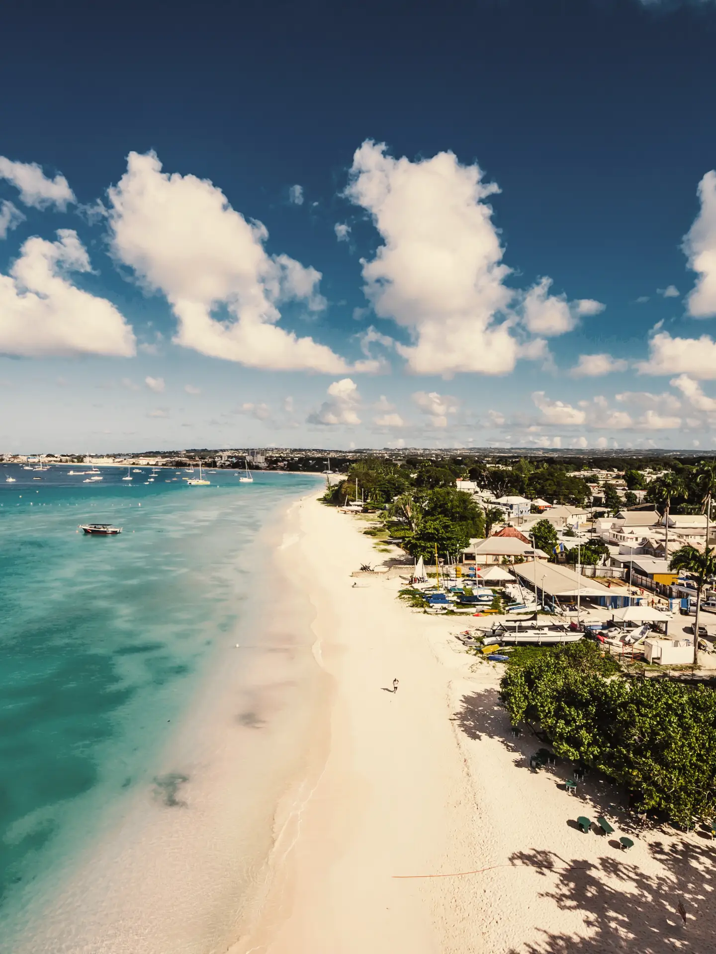 Küstenansicht von Barbados mit verschiedenen Städten entlang des Strandes und einigen Booten auf dem Wasser.
