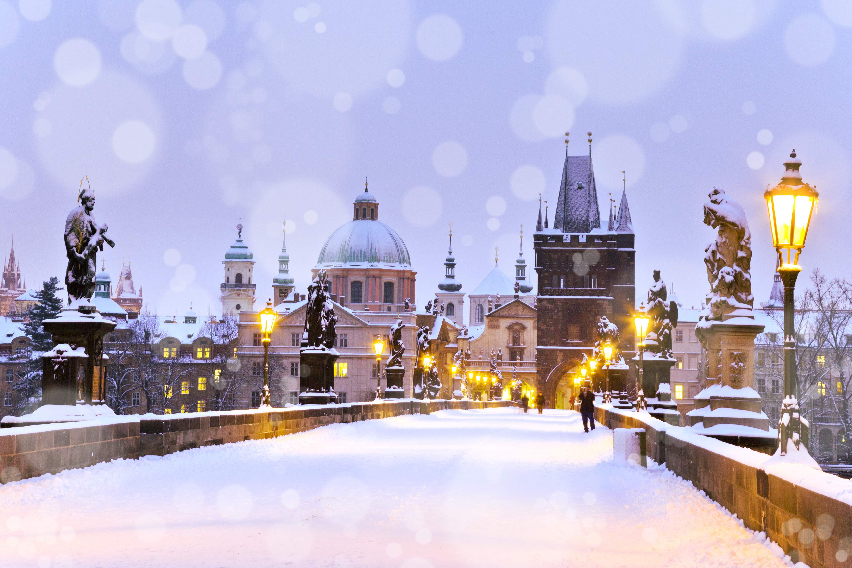 Charles Bridge and the Old Town Bridge Tower covered with snow in the evening in Prague