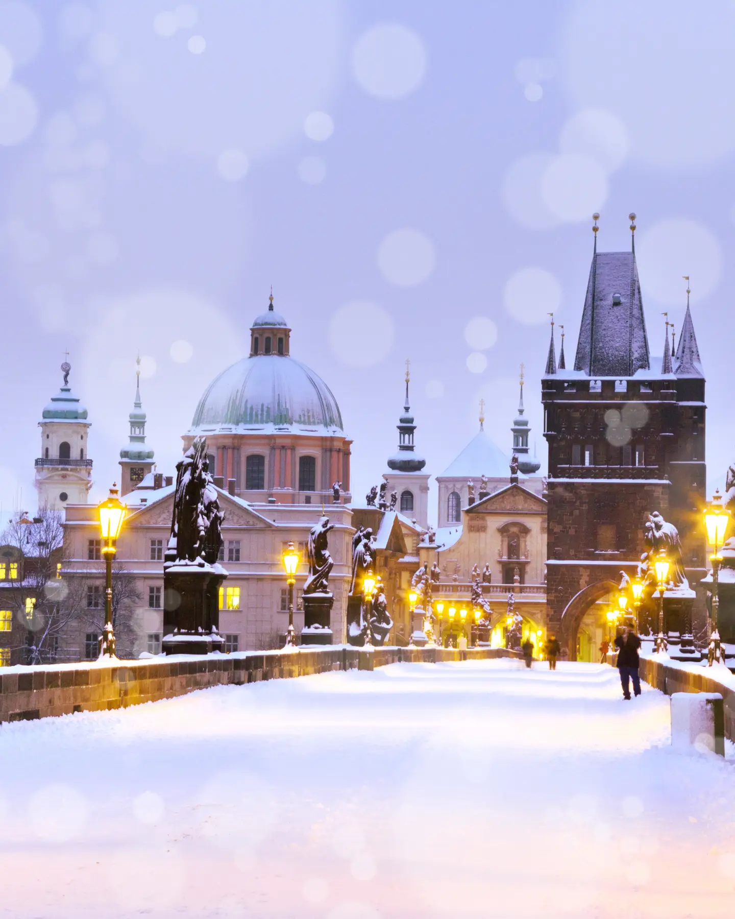 Charles Bridge and the Old Town Bridge Tower covered with snow in the evening in Prague