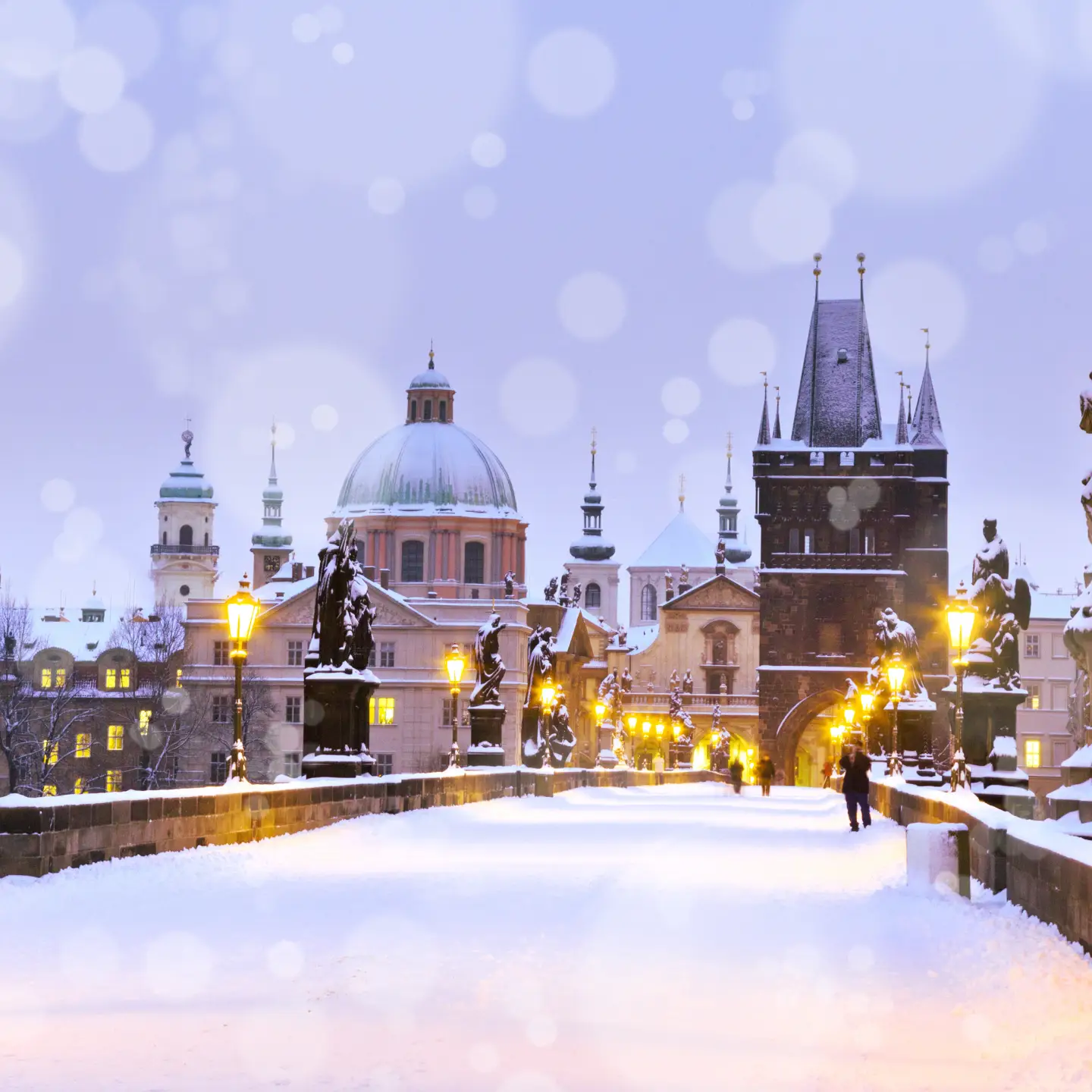 Charles Bridge and the Old Town Bridge Tower covered with snow in the evening in Prague