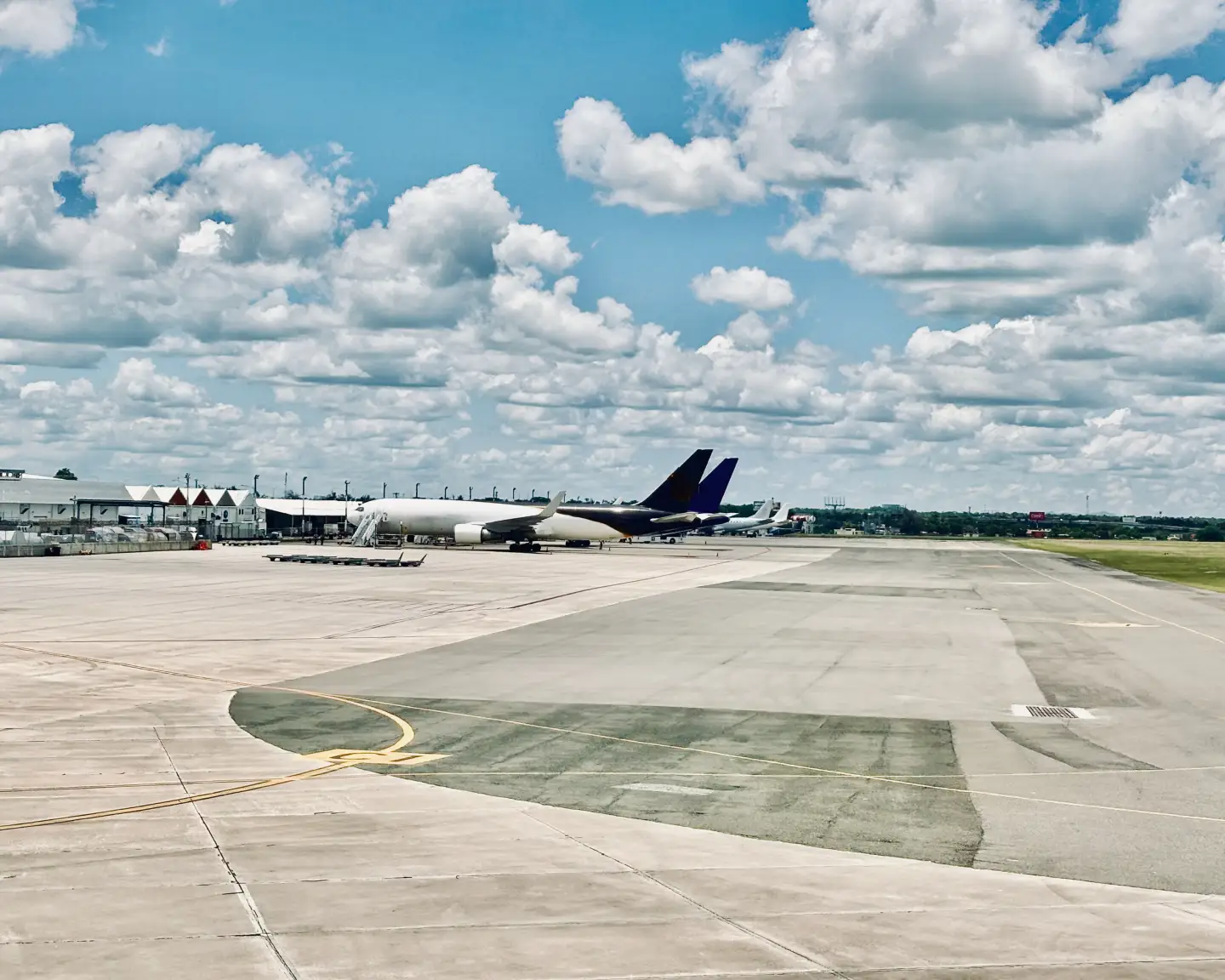 Una escena evocadora en el aeropuerto de Santo Domingo con aviones estacionados y majestuosas nubes en el cielo azul.