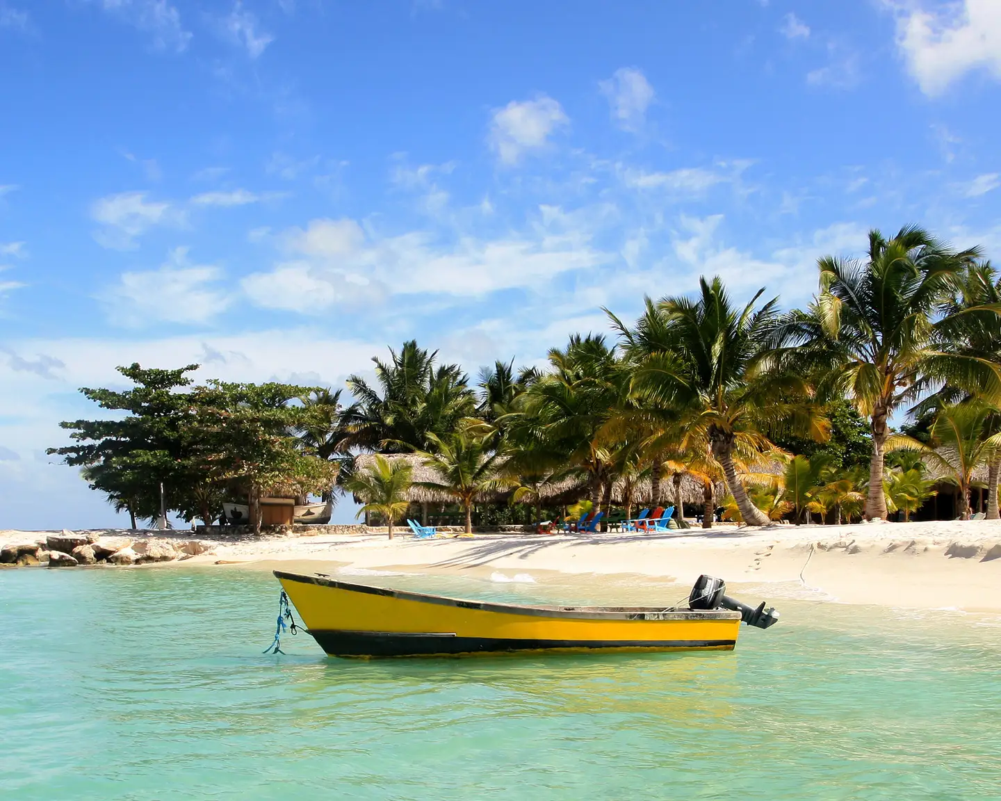 Bote amarillo en la playa de Bayahibe, República Dominicana, con palmeras y agua cristalina.