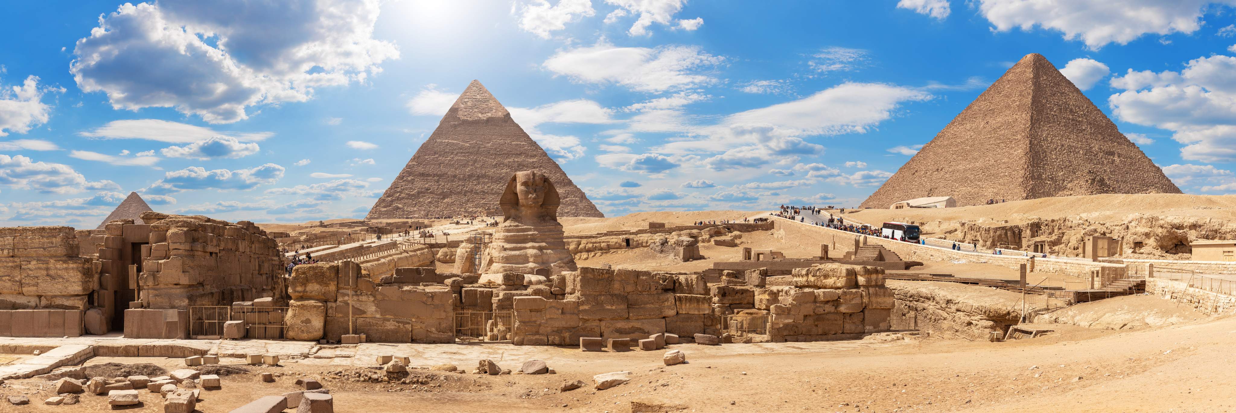 Blick auf die Große Sphinx und die Pyramiden von Gizeh bei Kairo unter blauem Himmel mit vereinzelten Wolken.