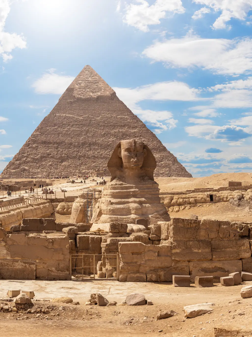 Blick auf die Große Sphinx und die Pyramiden von Gizeh bei Kairo unter blauem Himmel mit vereinzelten Wolken.