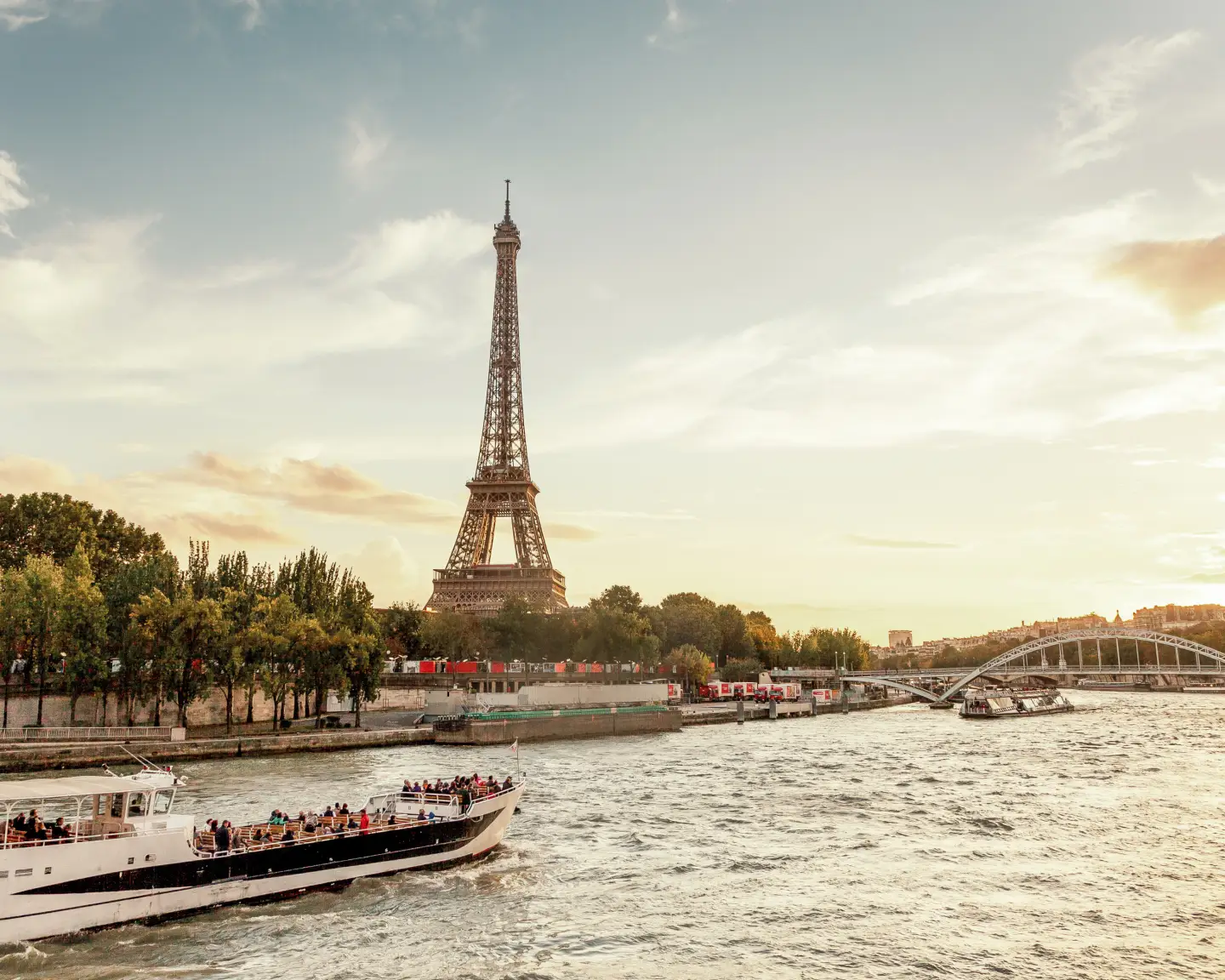 Tour Eiffel à Paris avec la Seine et un bateau d’excursion au coucher du soleil.