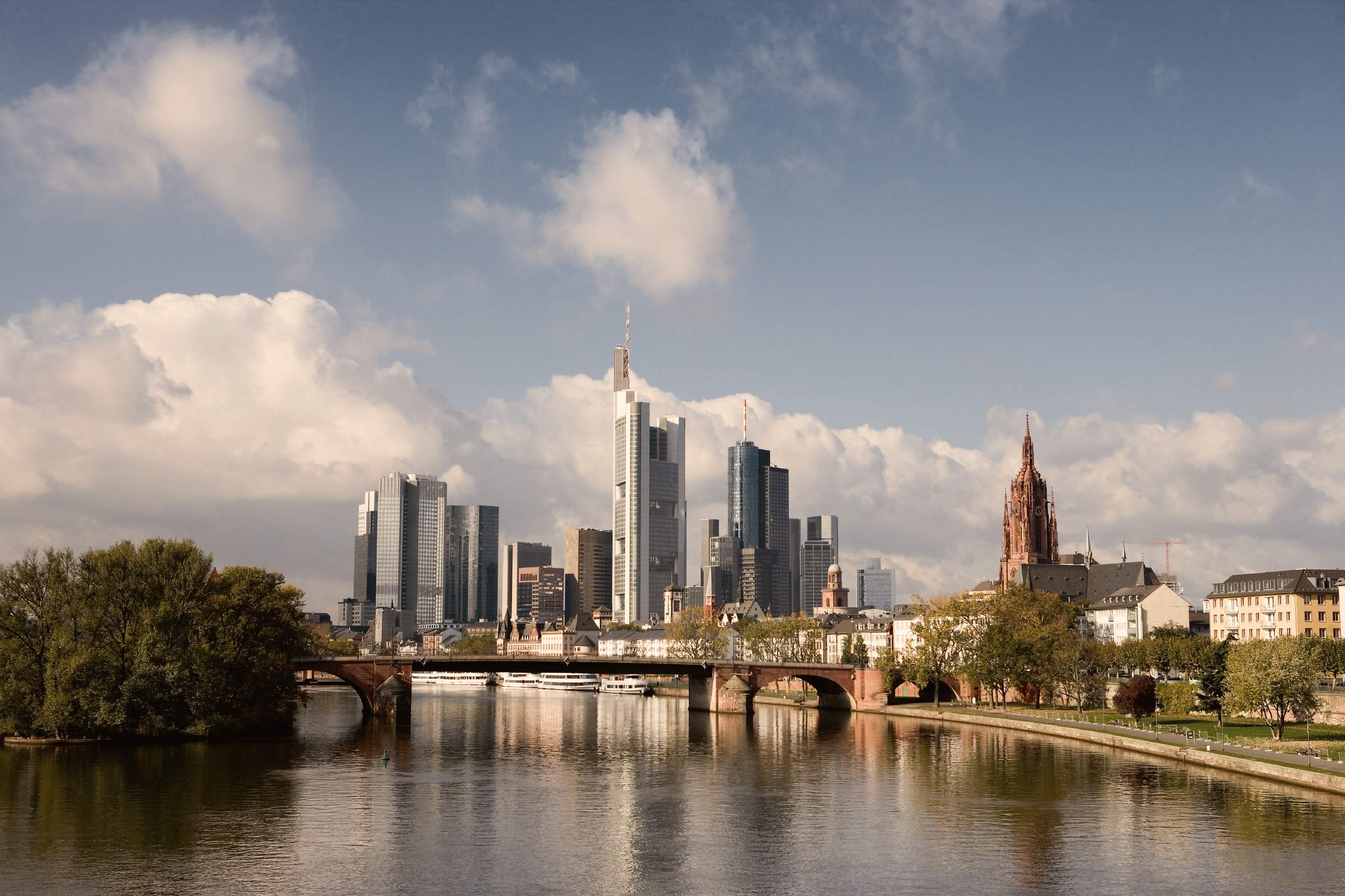 Blick auf die Frankfurter Skyline mit Main, historischen Brücken, Wolkenkratzern und dem Kaiserdom St. Bartholomäus.