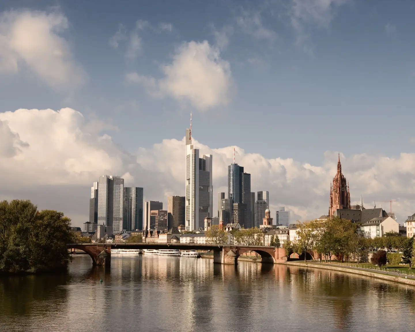 Blick auf die Frankfurter Skyline mit Main, historischen Brücken, Wolkenkratzern und dem Kaiserdom St. Bartholomäus.