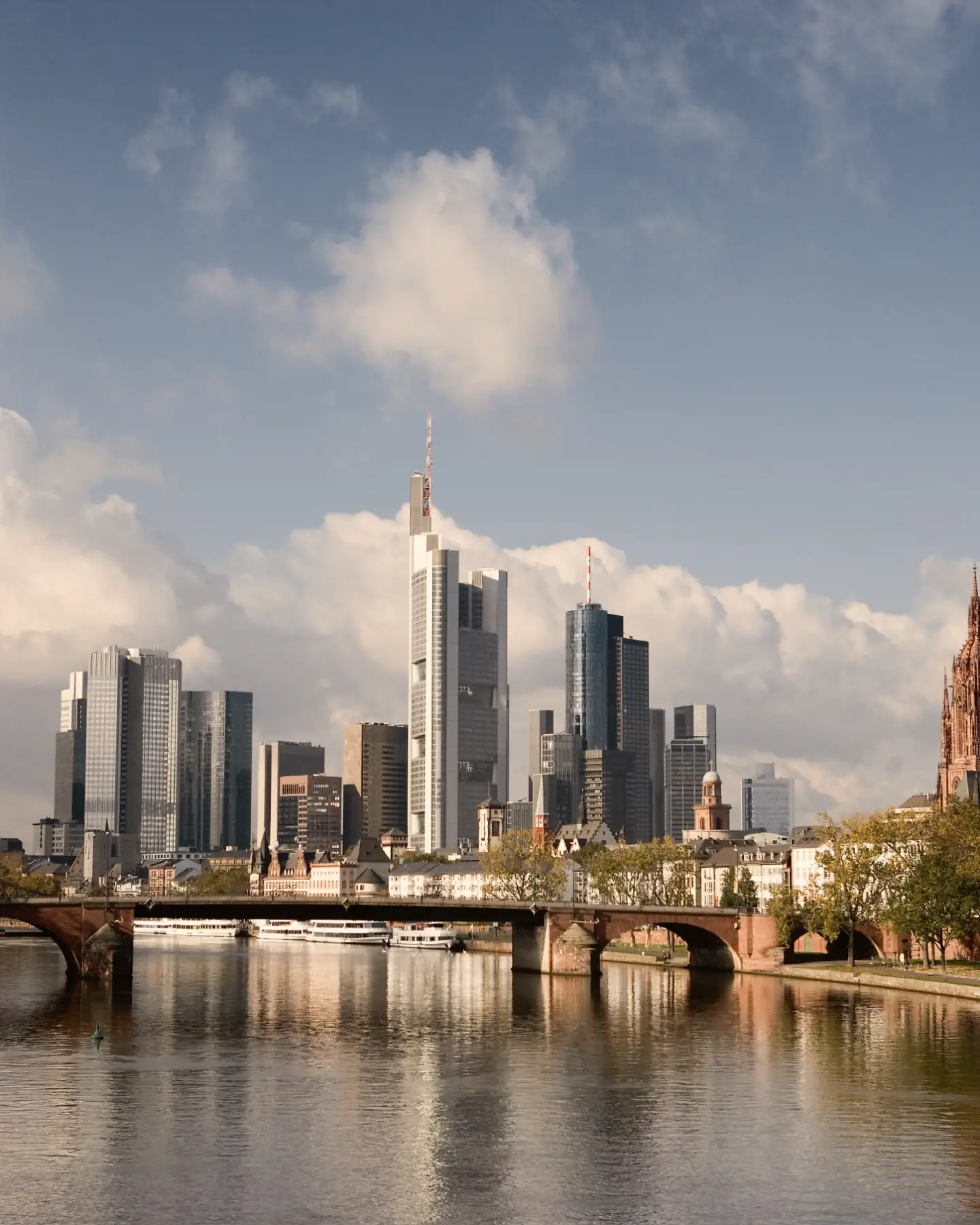 Blick auf die Frankfurter Skyline mit Main, historischen Brücken, Wolkenkratzern und dem Kaiserdom St. Bartholomäus.