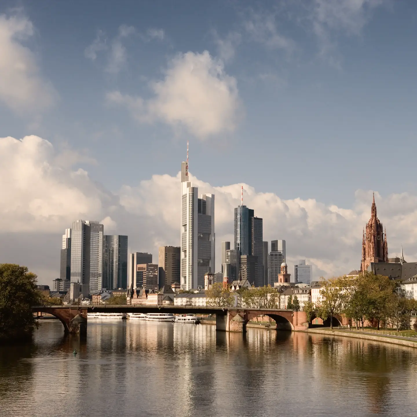Blick auf die Frankfurter Skyline mit Main, historischen Brücken, Wolkenkratzern und dem Kaiserdom St. Bartholomäus.