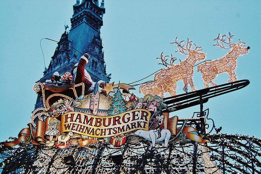 Un cartel luminoso sobre un acogedor puesto en el mercado navideño de Hamburgo