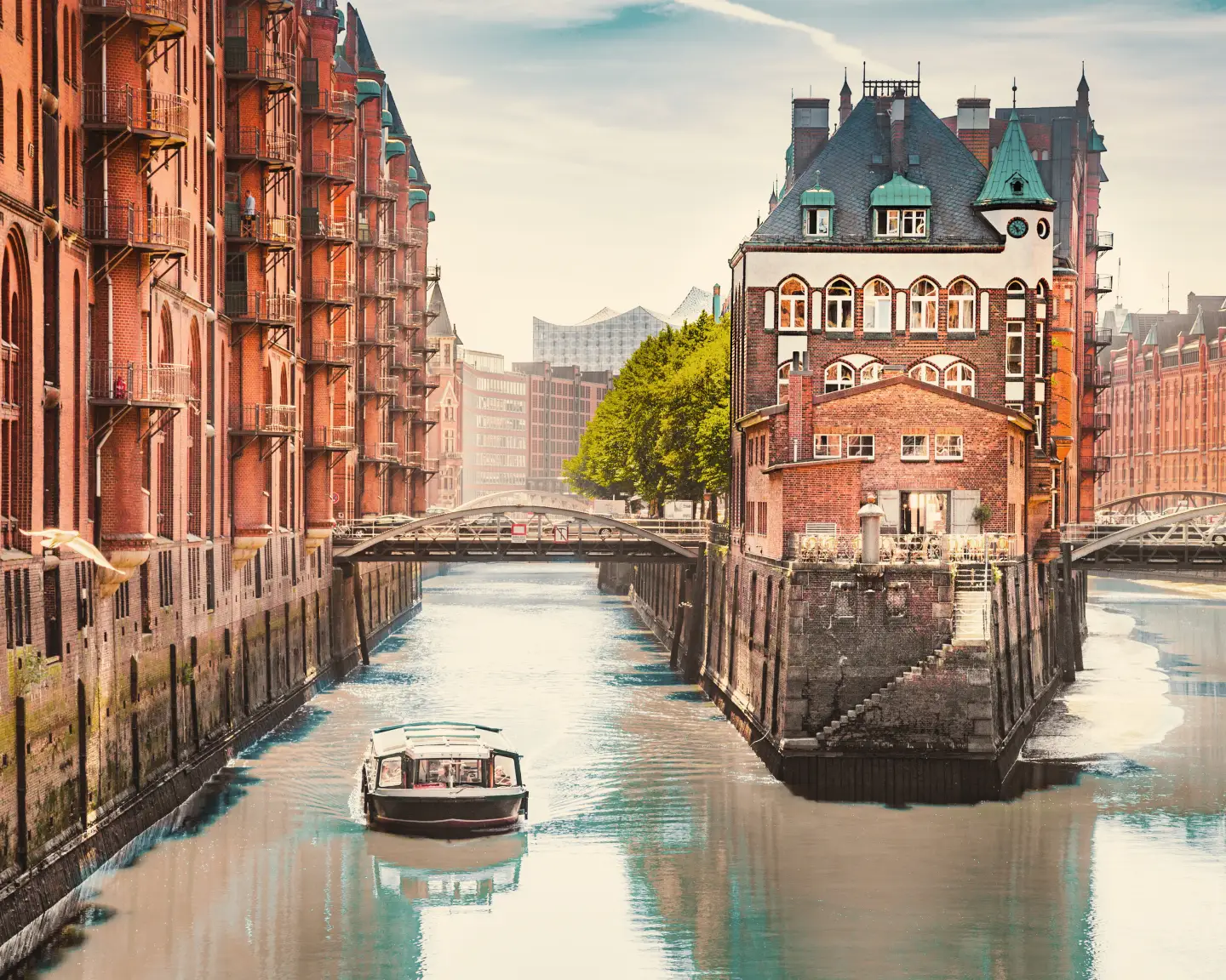Historische Backsteingebäude und Kanäle der Hamburger Speicherstadt mit der Elbphilharmonie im Hintergrund.