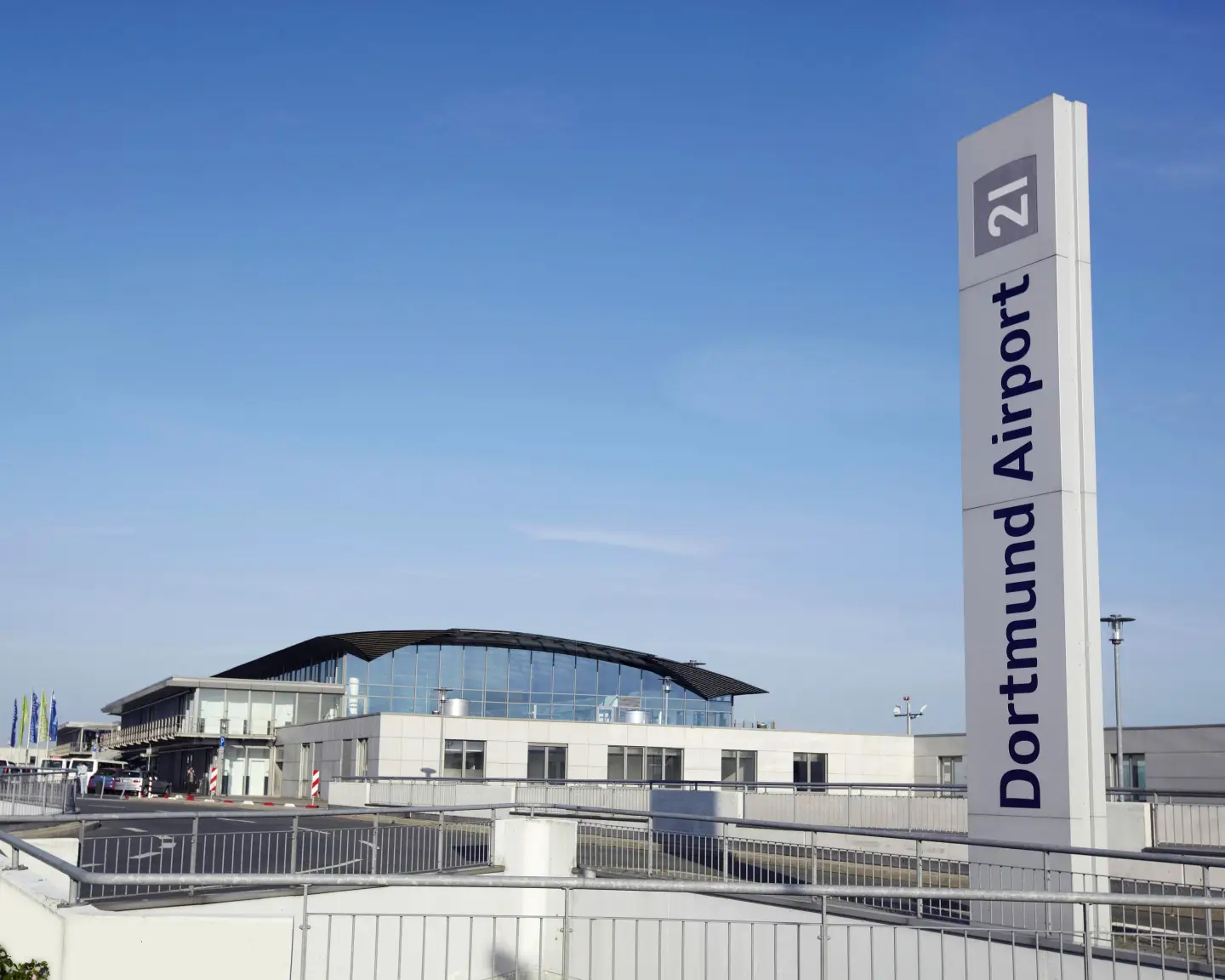 Stéla s logem letiště Dortmund u vchodu do areálu letiště.