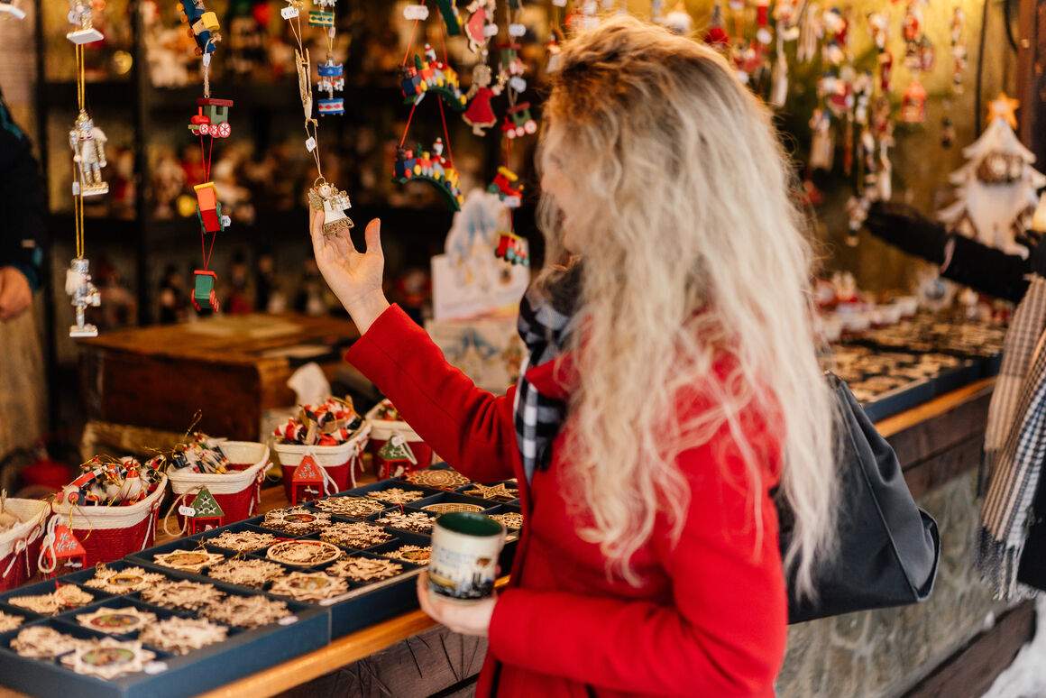 A woman looks at small decorations at a Christmas market stall in Munich