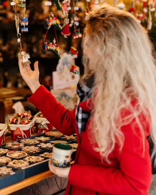 A woman looks at small decorations at a Christmas market stall in Munich