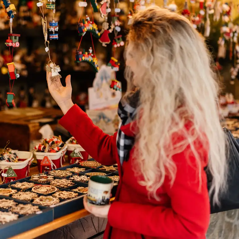 A woman looks at small decorations at a Christmas market stall in Munich