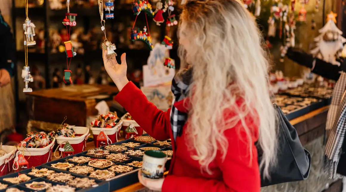 A woman looks at small decorations at a Christmas market stall in Munich