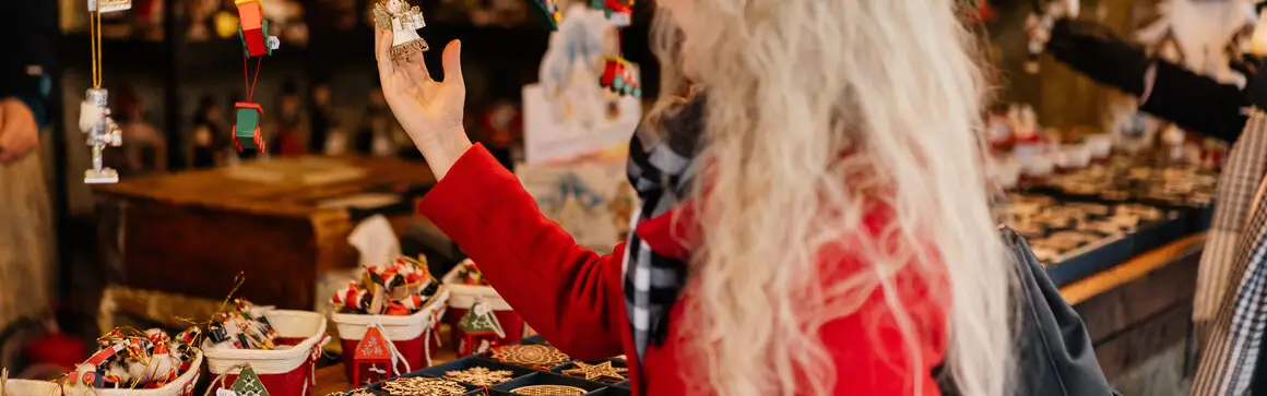 A woman looks at small decorations at a Christmas market stall in Munich