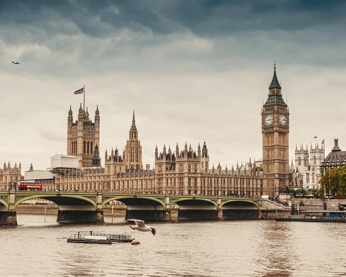 Big Ben a budovy parlamentu v Londýně s Temží v popředí.