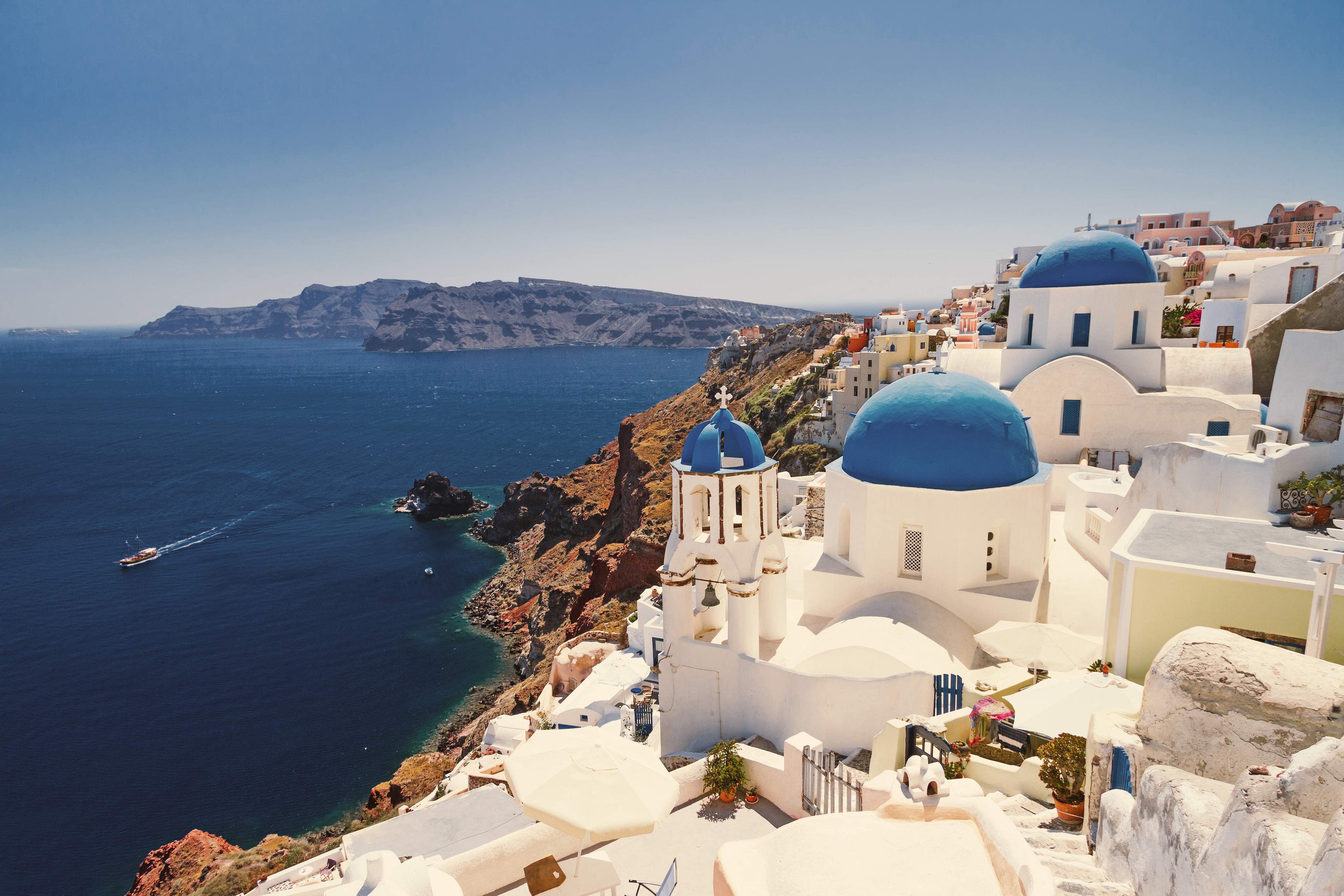 Blick auf Santorinis ikonische weiße Häuser mit blauen Kuppeln, die auf das Ägäische Meer blicken.