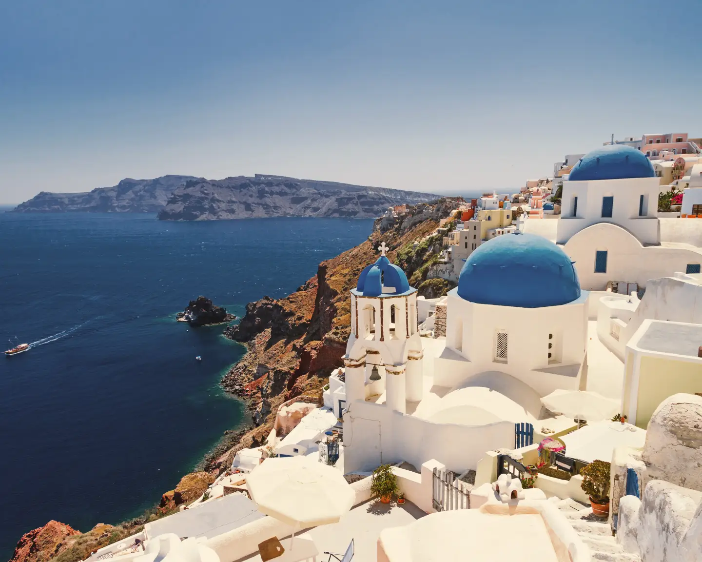Blick auf Santorinis ikonische weiße Häuser mit blauen Kuppeln, die auf das Ägäische Meer blicken.