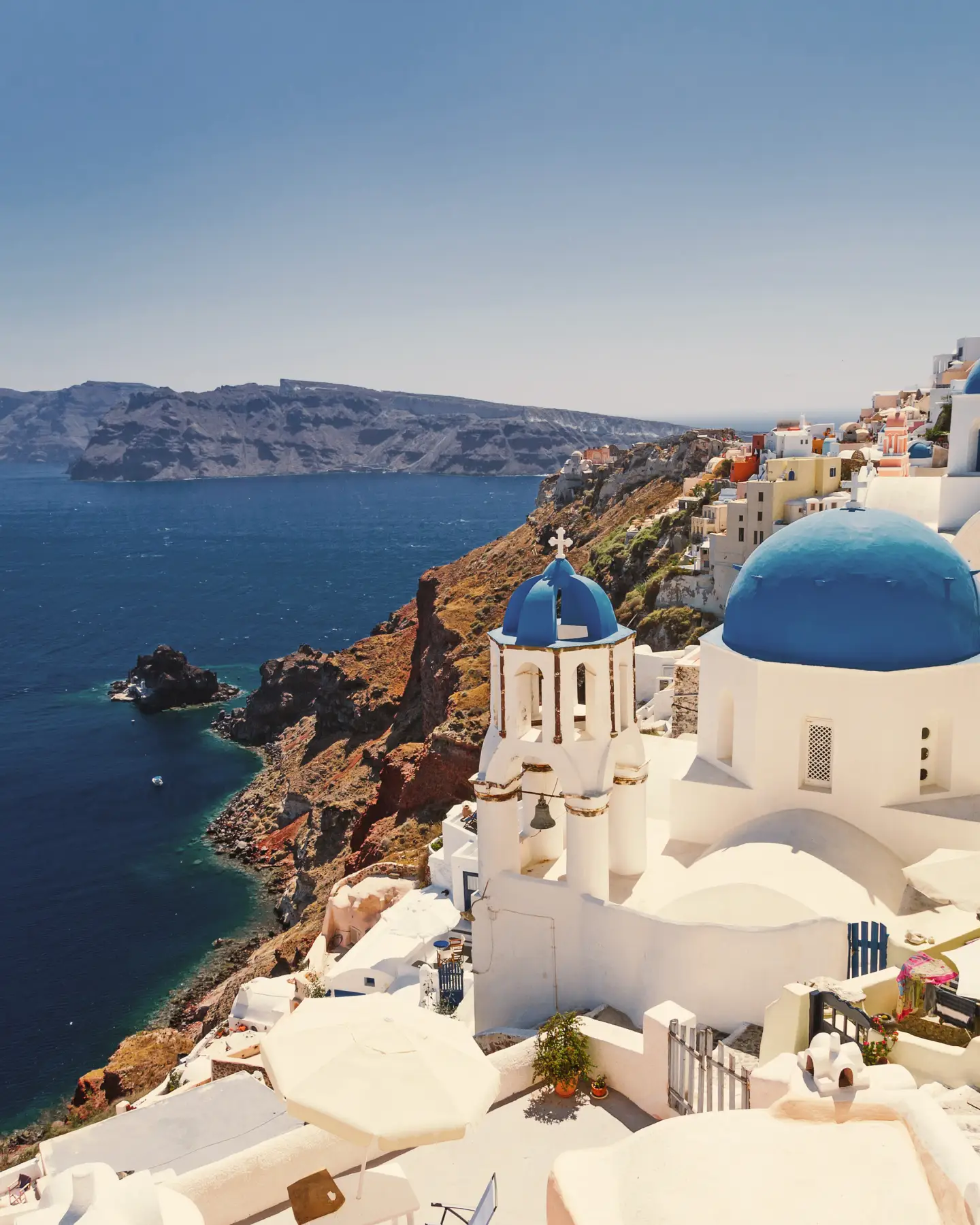 Blick auf Santorinis ikonische weiße Häuser mit blauen Kuppeln, die auf das Ägäische Meer blicken.