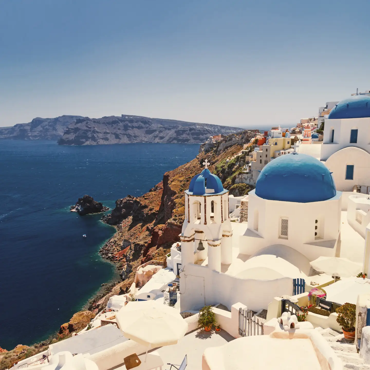 Blick auf Santorinis ikonische weiße Häuser mit blauen Kuppeln, die auf das Ägäische Meer blicken.