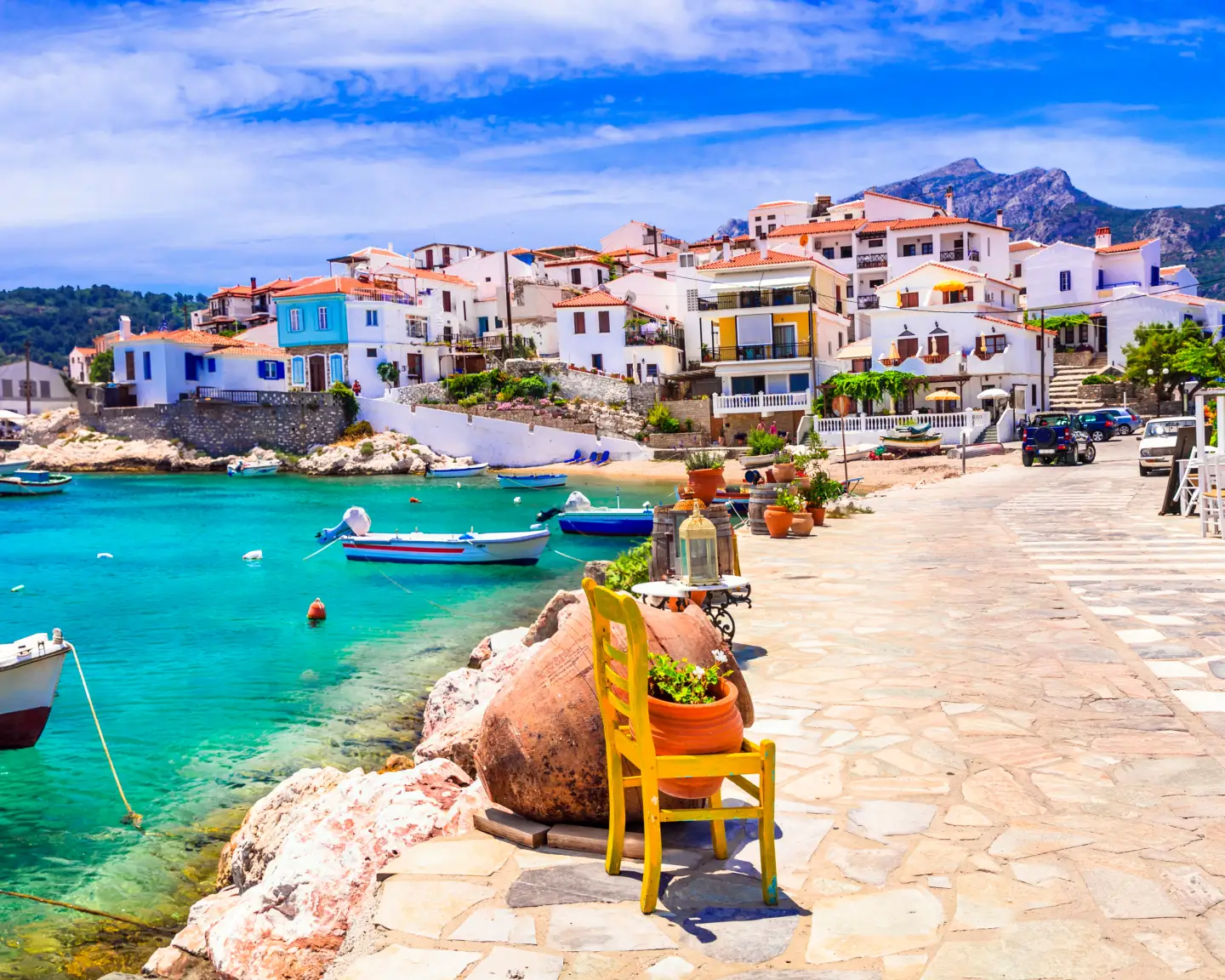 Pueblo costero de Kokkari, en Samos, Grecia, con casas de colores, mar turquesa y barcos pesqueros en el puerto.