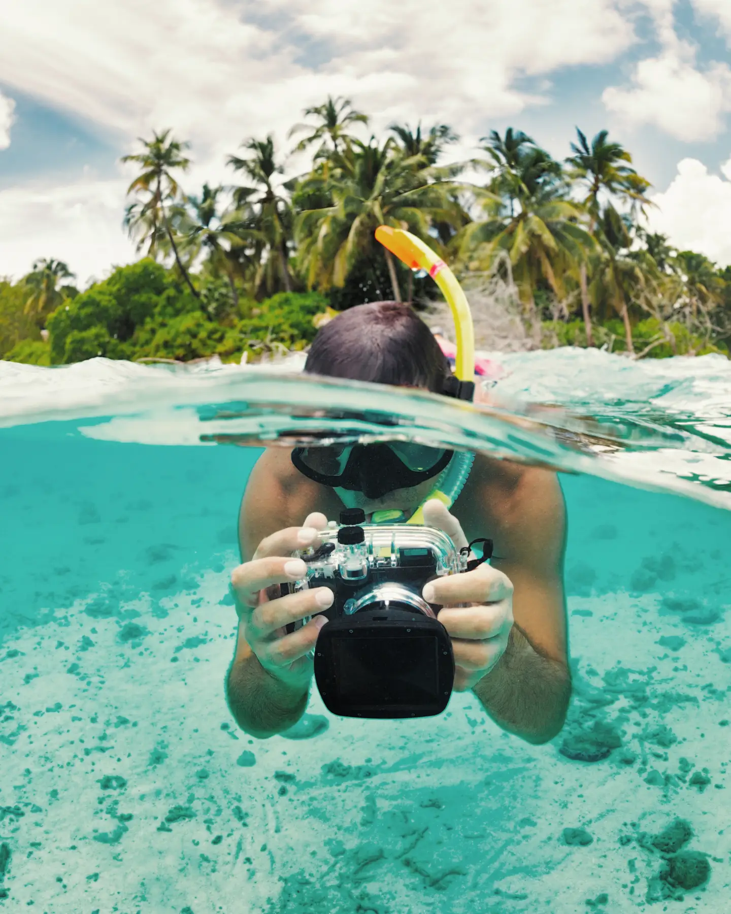 Un buceador con un snorkel y cámara subacuática hace fotos al ras del agua en una isla tropical. Un buceador con un snorkel y cámara subacuática hace fotos al ras del agua en una isla tropical.