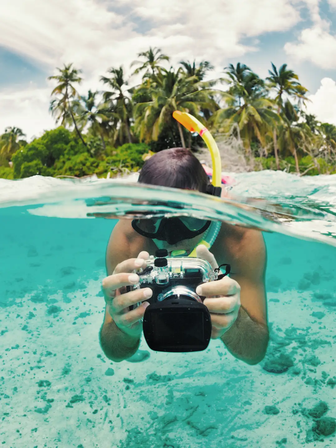 Une personne pratiquant le snorkeling avec un appareil photo aux Maldives